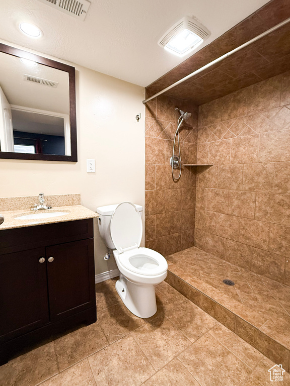 Full bath featuring tiled shower, toilet, baseboards, and vanity