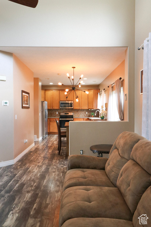 Living area featuring a chandelier, dark wood finished floors, and baseboards