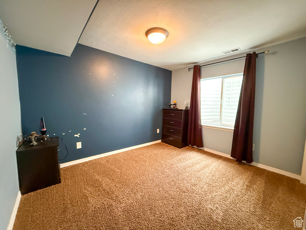 Bedroom featuring carpet, baseboards, and a textured ceiling