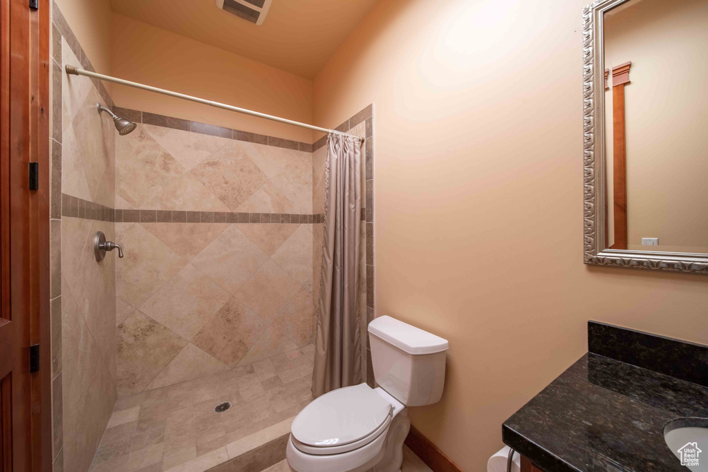 Full bathroom with toilet, vanity, and tiled shower