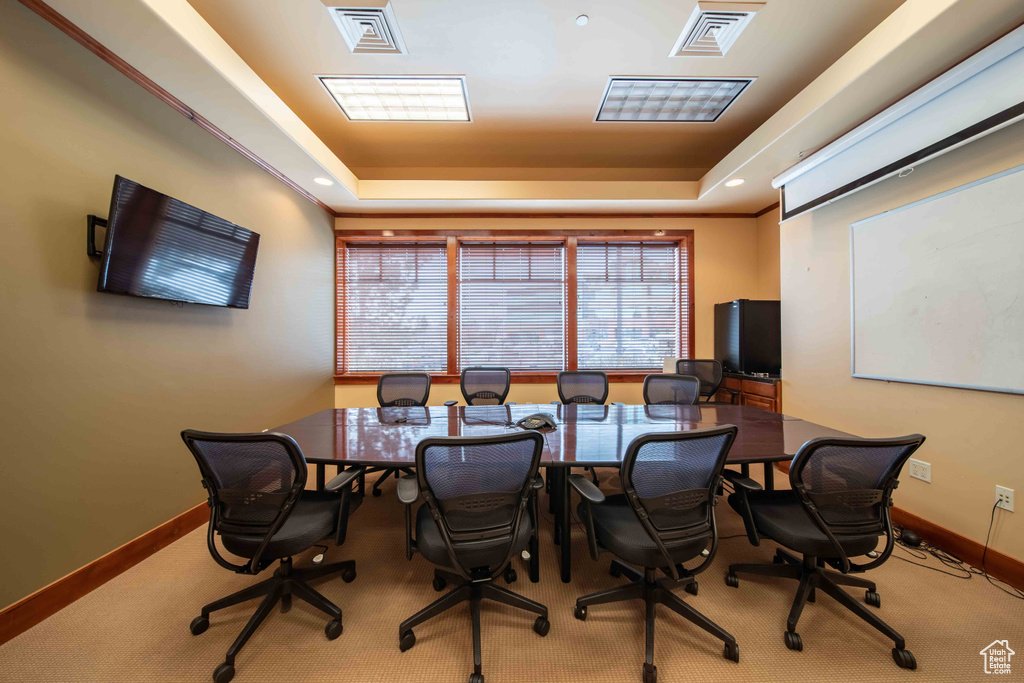 Office space with a tray ceiling, baseboards, and carpet flooring