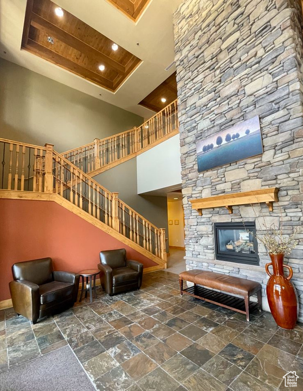 Living room featuring stone tile flooring, stairs, recessed lighting, baseboards, and a towering ceiling