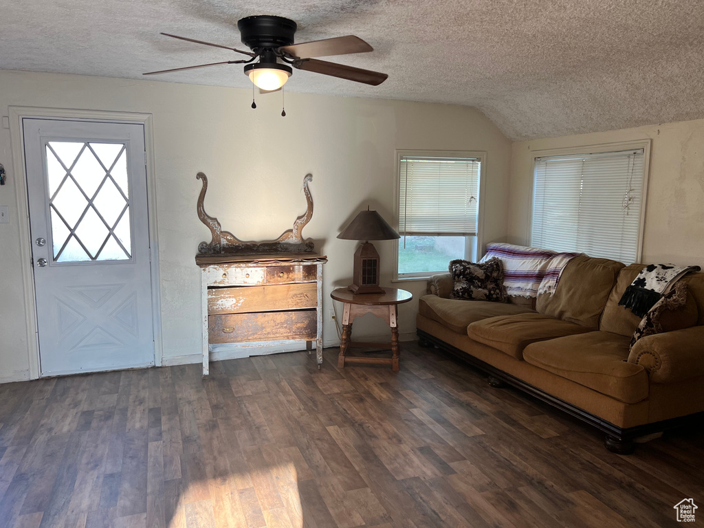 Living room with a textured ceiling, dark wood-style floors, plenty of natural light, a ceiling fan, and vaulted ceiling