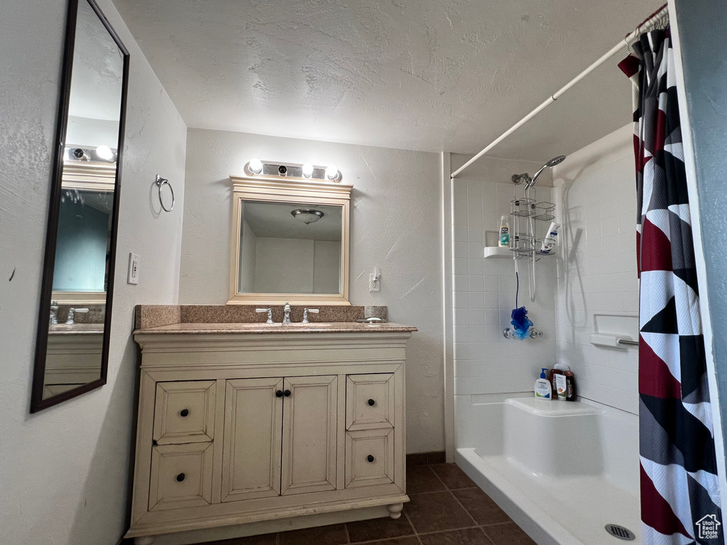 Bathroom featuring a shower with shower curtain, tile patterned floors, vanity, and a textured ceiling