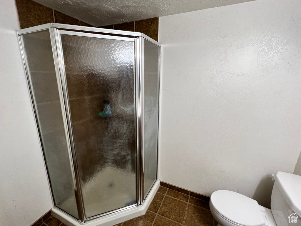 Bathroom featuring a stall shower, toilet, and tile patterned flooring