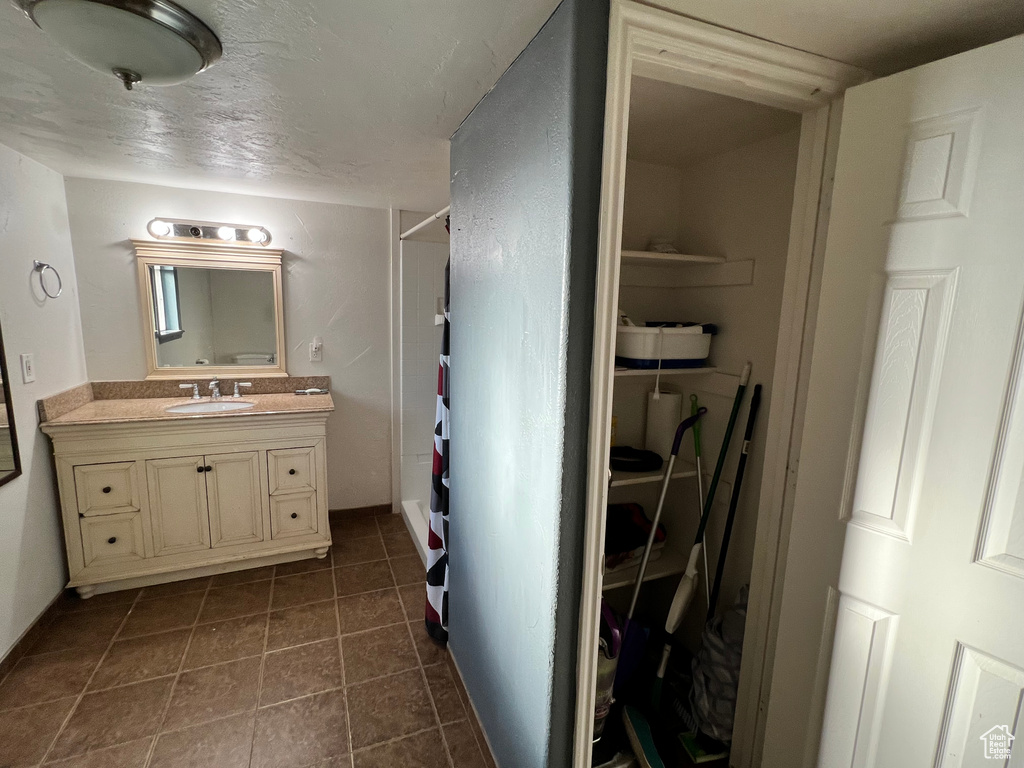 Bathroom featuring vanity, curtained shower, tile patterned flooring, and a textured ceiling