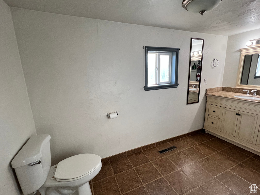 Bathroom featuring toilet, vanity, tile patterned flooring, and baseboards