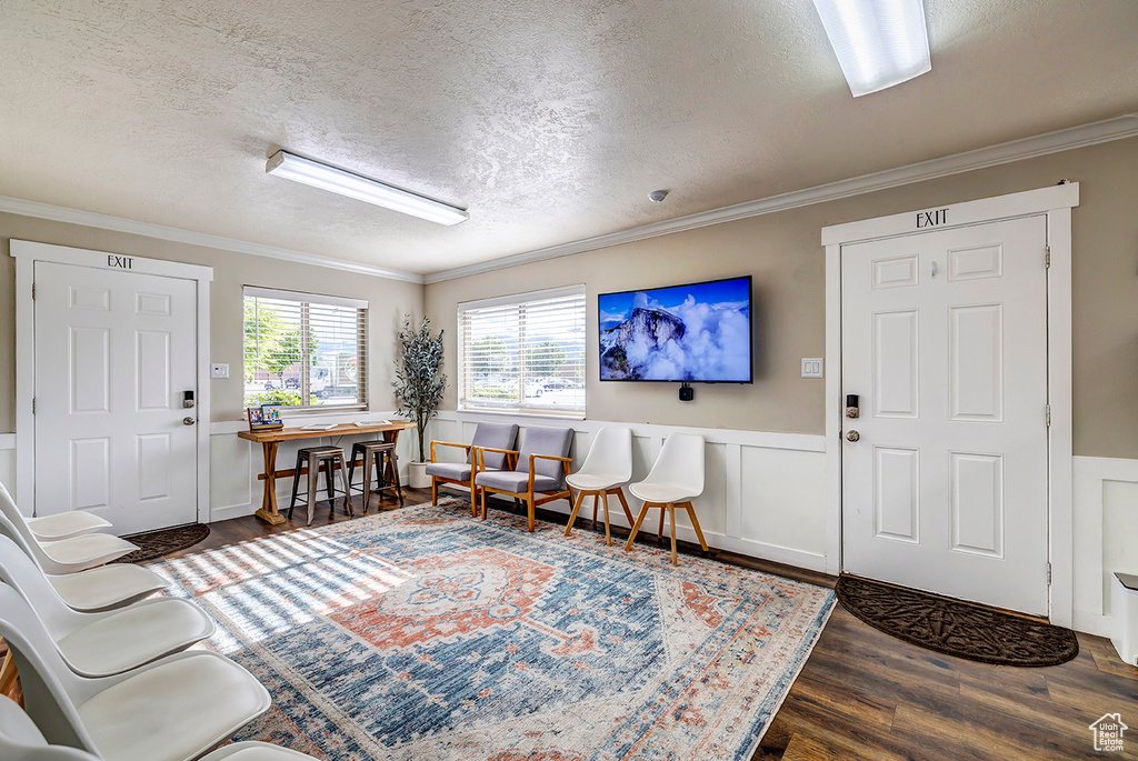 Entryway featuring a textured ceiling, wood finished floors, crown molding, and wainscoting