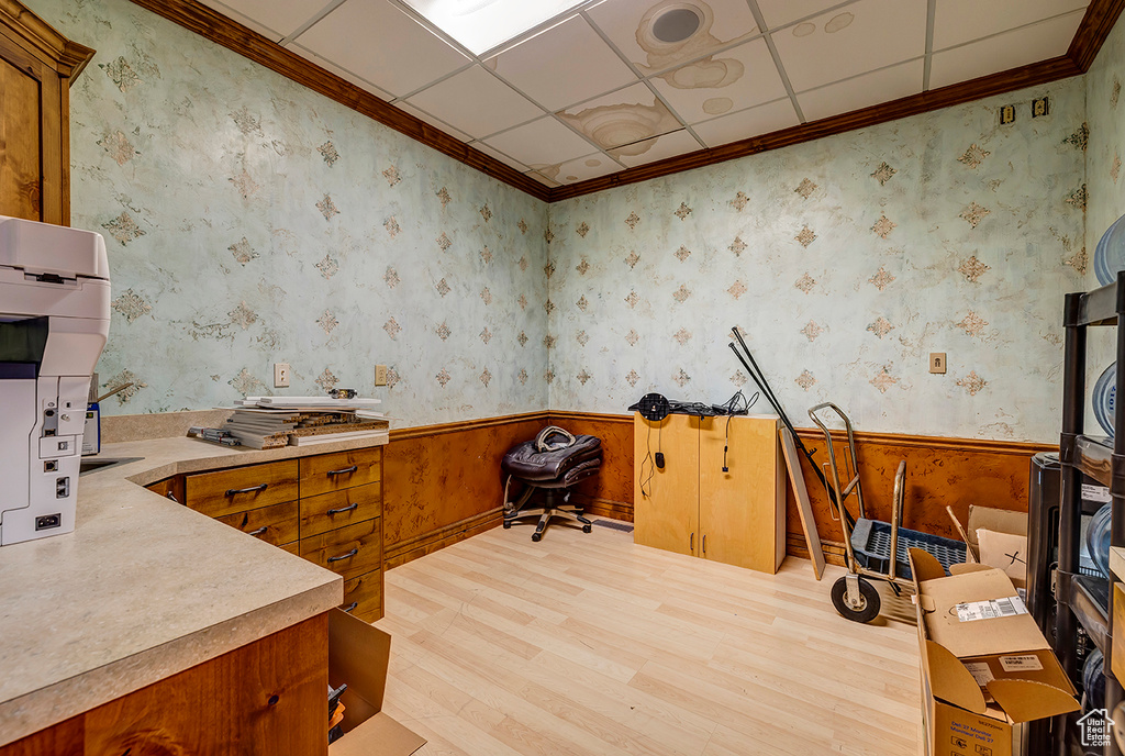 Home office featuring light wood-type flooring, a wainscoted wall, and ornamental molding