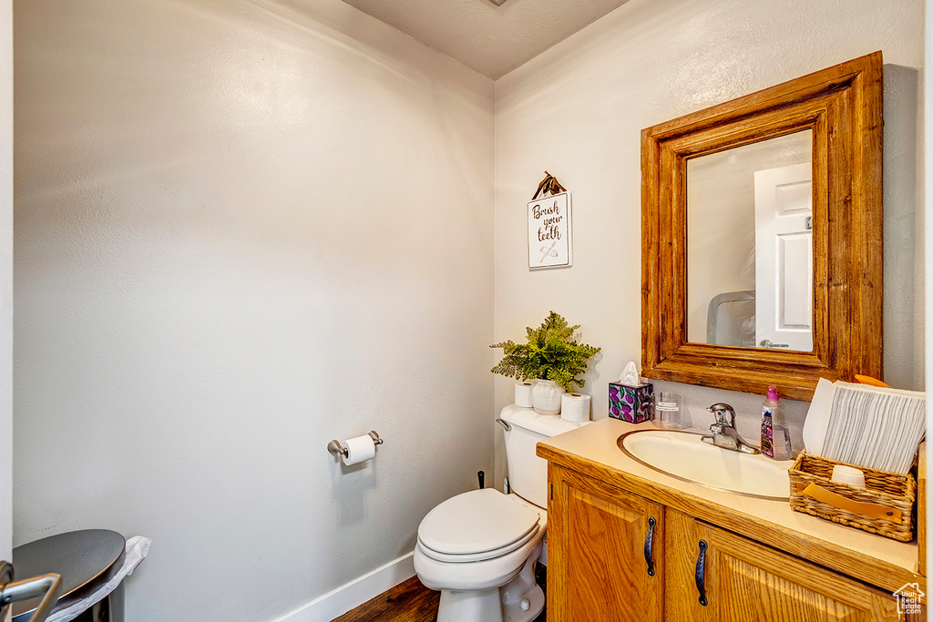 Bathroom featuring toilet, wood finished floors, vanity, and baseboards