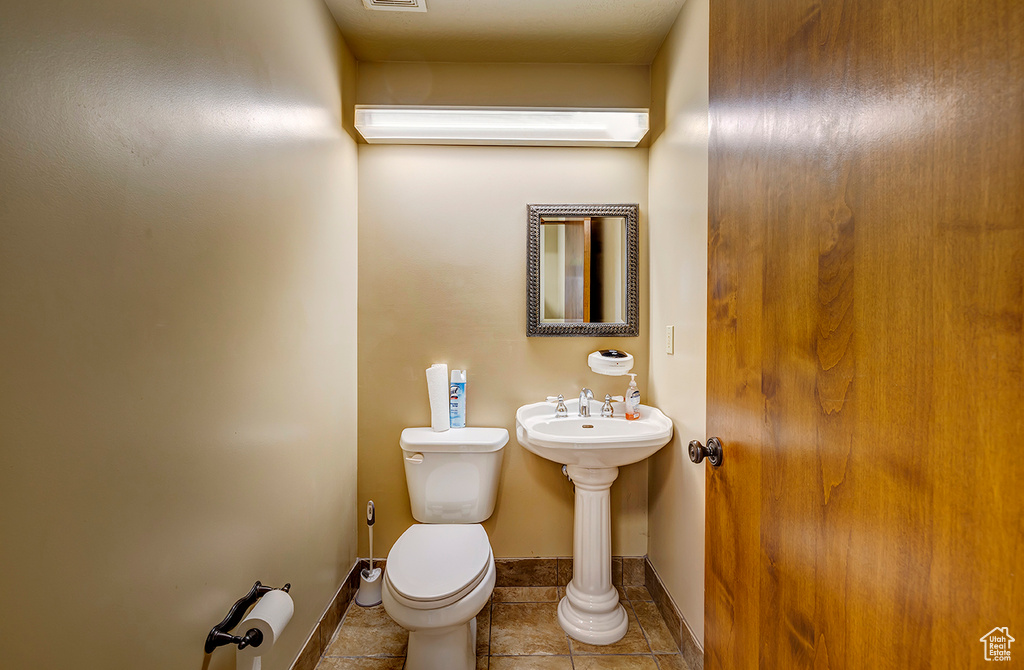 Half bath featuring toilet, baseboards, and tile patterned flooring