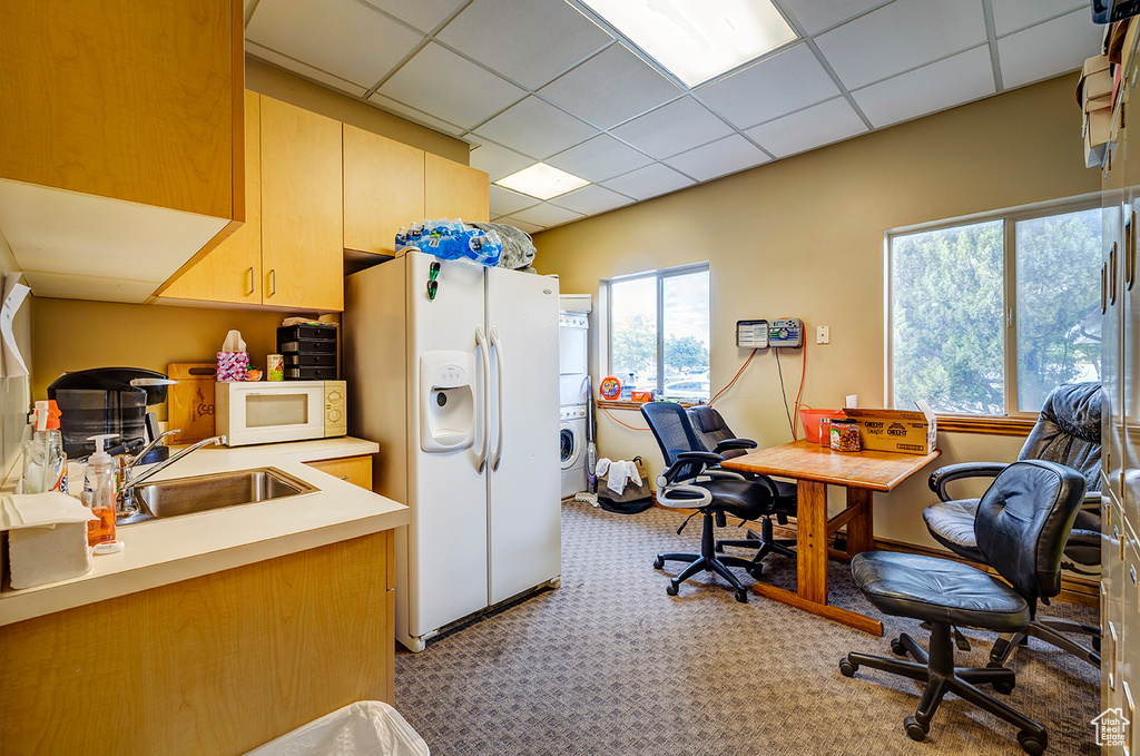 Office with stacked washer and clothes dryer, light carpet, a sink, healthy amount of natural light, and a drop ceiling