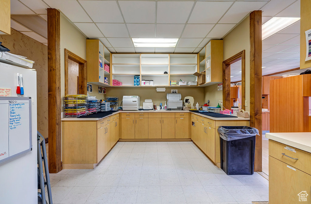 Kitchen with a paneled ceiling, open shelves, light brown cabinets, light floors, and light countertops