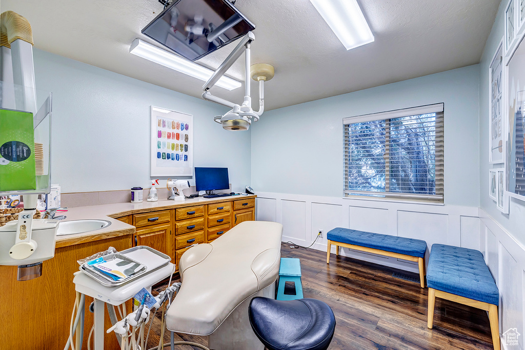 Office with wainscoting, dark wood-type flooring, and a decorative wall