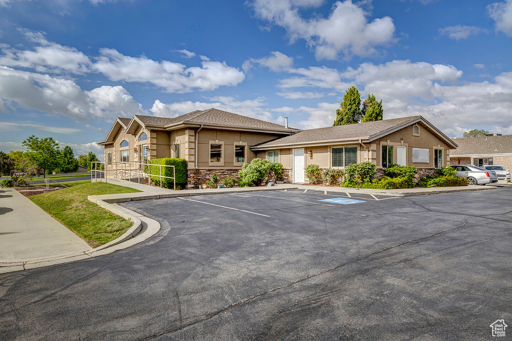 View of front of property with stucco siding, uncovered parking, and stone siding