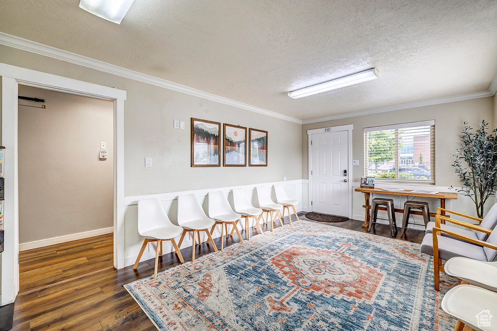 Foyer entrance featuring a textured ceiling, wood finished floors, ornamental molding, and baseboards
