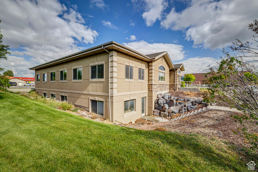 Rear view of house featuring a yard and stucco siding