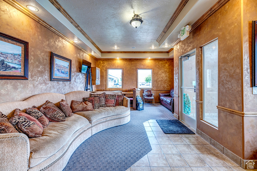 Living area featuring ornamental molding, a textured ceiling, light tile patterned floors, light carpet, and baseboards