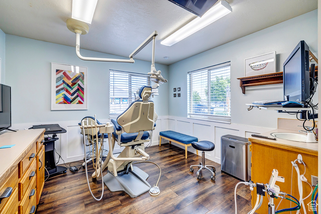 Exercise room featuring plenty of natural light, a wainscoted wall, and dark wood-style floors
