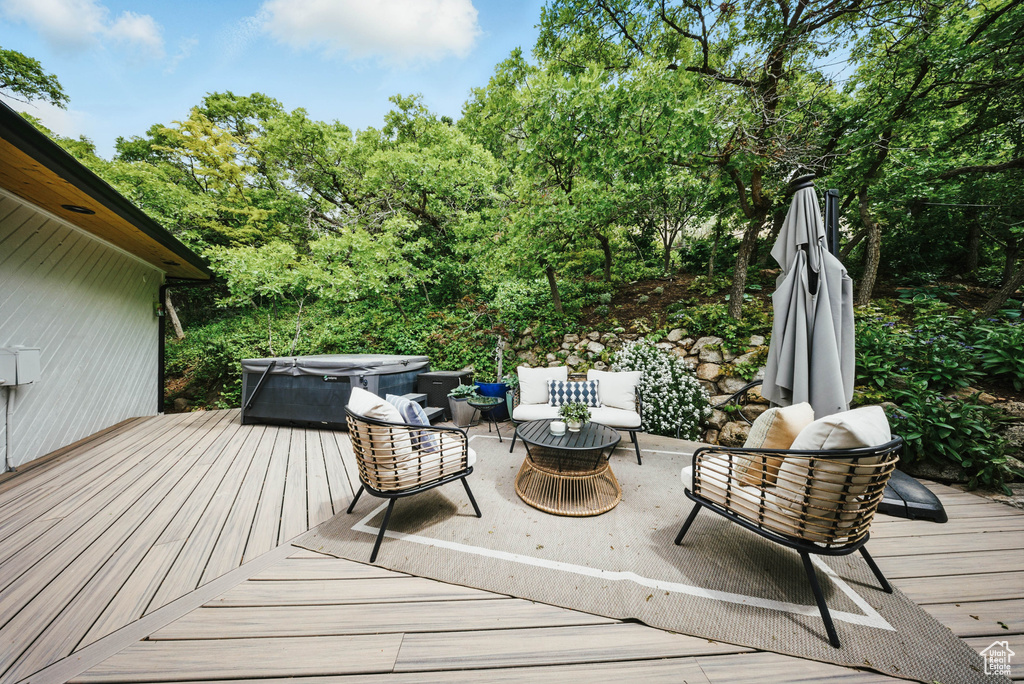 Wooden deck featuring a hot tub, an outdoor hangout area, and view of scattered trees