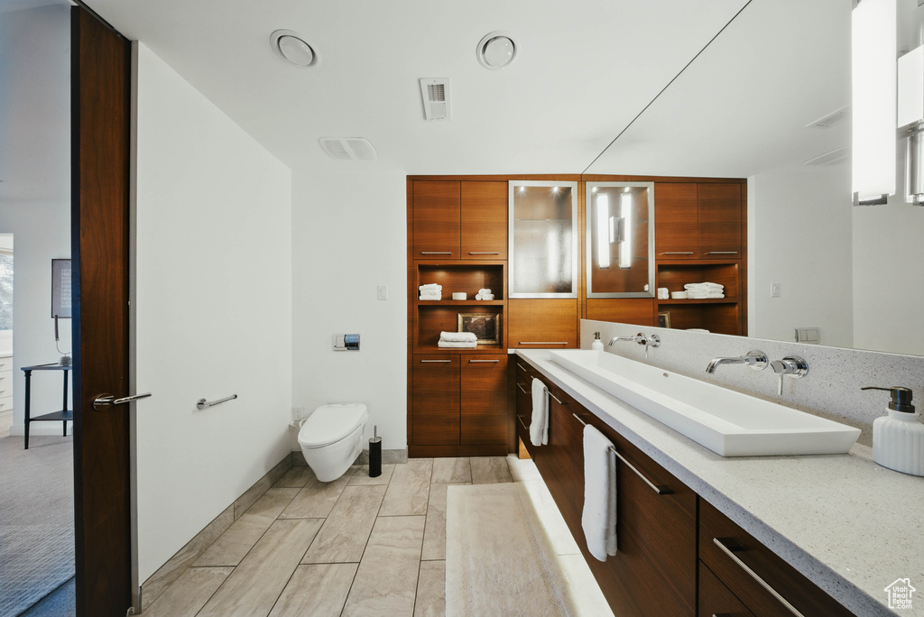 Bathroom featuring toilet, vanity, and baseboards