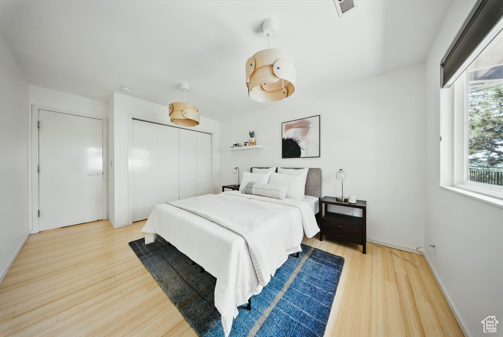Bedroom with wood finished floors, a closet, and baseboards