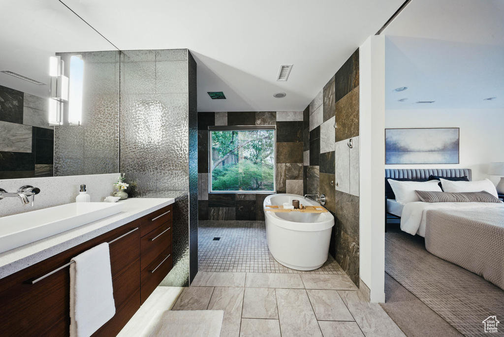 Ensuite bathroom with tile walls, a freestanding tub, vanity, and walk in shower