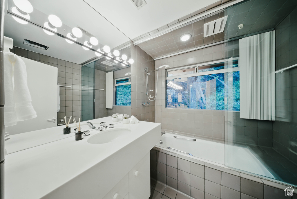 Full bath featuring tiled shower / bath, tile walls, vanity, and tile patterned floors