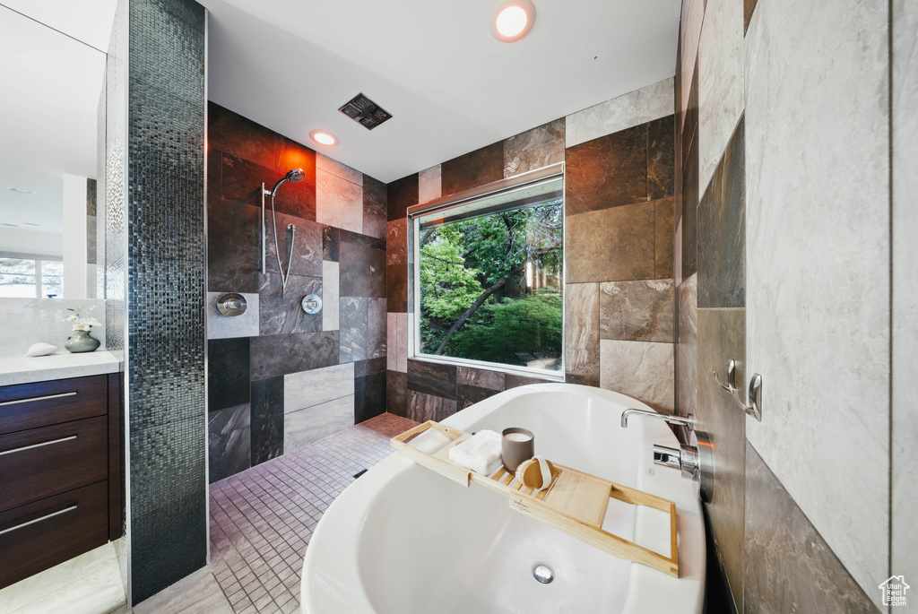 Full bathroom featuring tile walls, a bathtub, tiled shower, healthy amount of natural light, and recessed lighting
