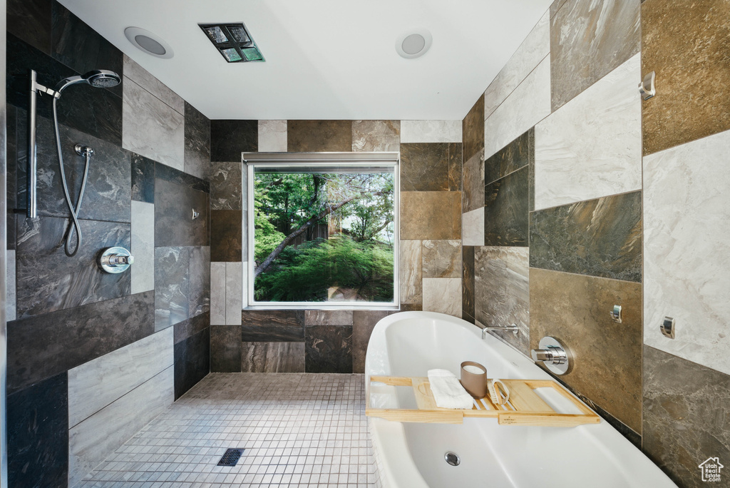 Bathroom with a soaking tub, tile walls, and tiled shower