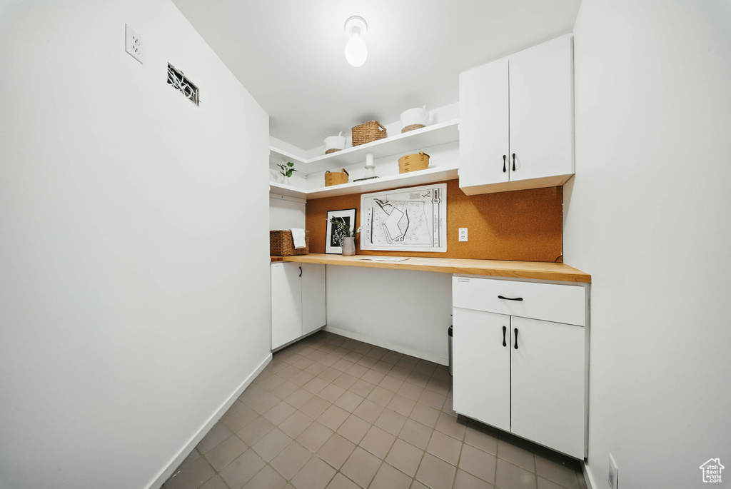 Kitchen featuring open shelves, light tile patterned flooring, white cabinets, baseboards, and butcher block counters