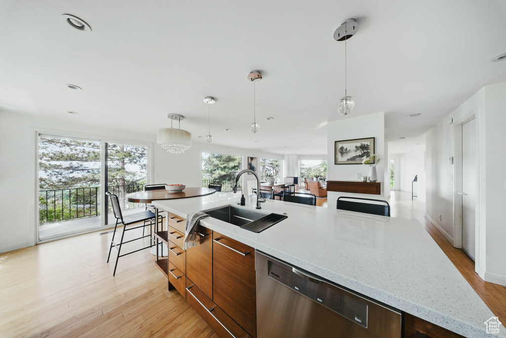 Kitchen with dishwasher, a sink, modern cabinets, light wood-style floors, and hanging light fixtures