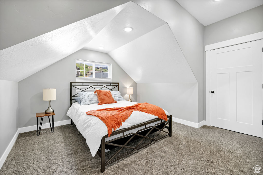 Bedroom with carpet, baseboards, lofted ceiling, and a textured ceiling