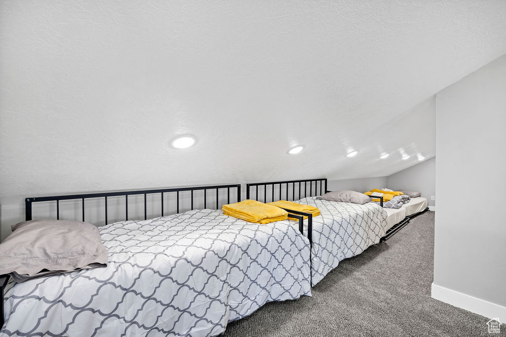 Carpeted bedroom featuring baseboards and lofted ceiling