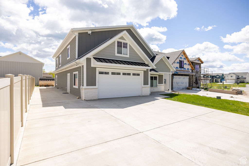 View of front of house featuring a garage, a standing seam roof, concrete driveway, metal roof, and board and batten siding