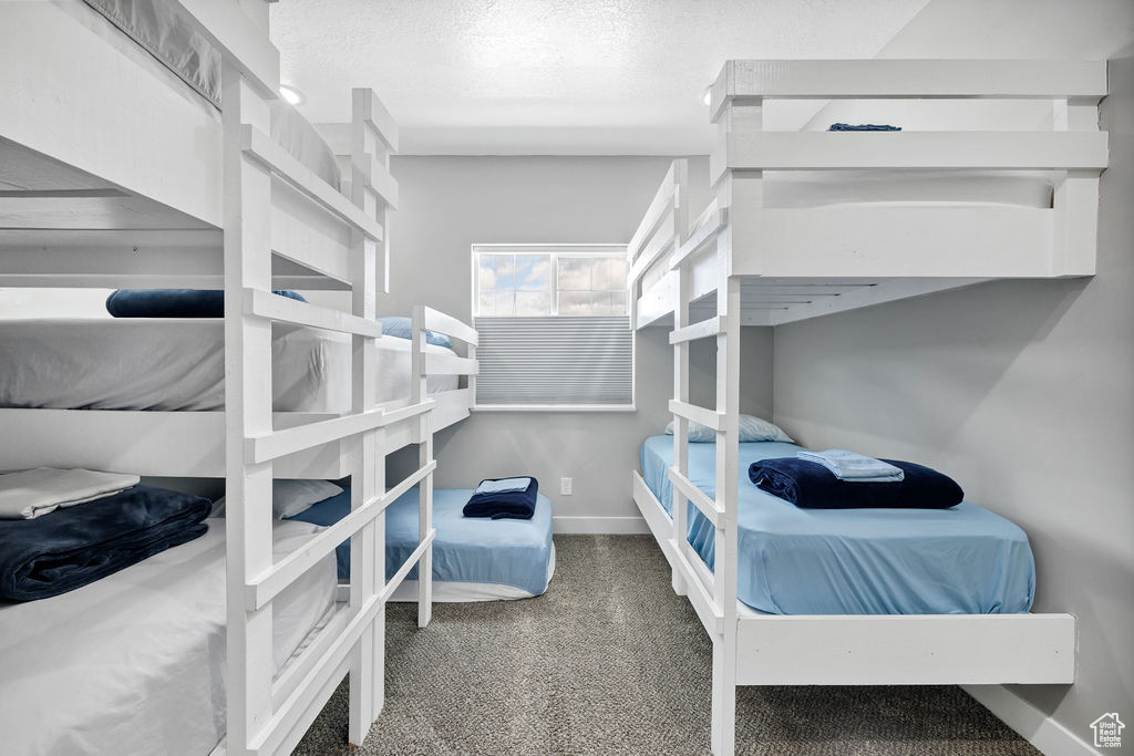 Bedroom with carpet floors, baseboards, and a textured ceiling
