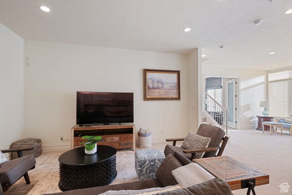 Living area featuring recessed lighting, carpet flooring, baseboards, stairway, and a textured ceiling