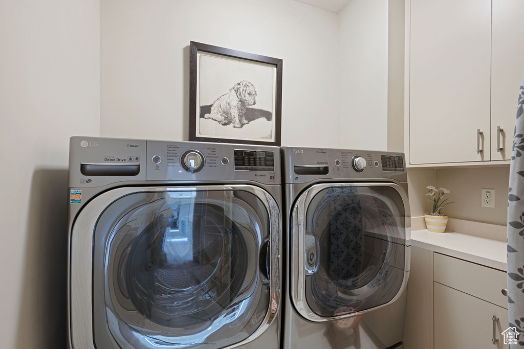 Washroom featuring separate washer and dryer and cabinet space