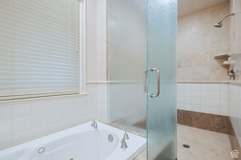 Full bathroom with a shower stall, a tub with jets, and tile walls