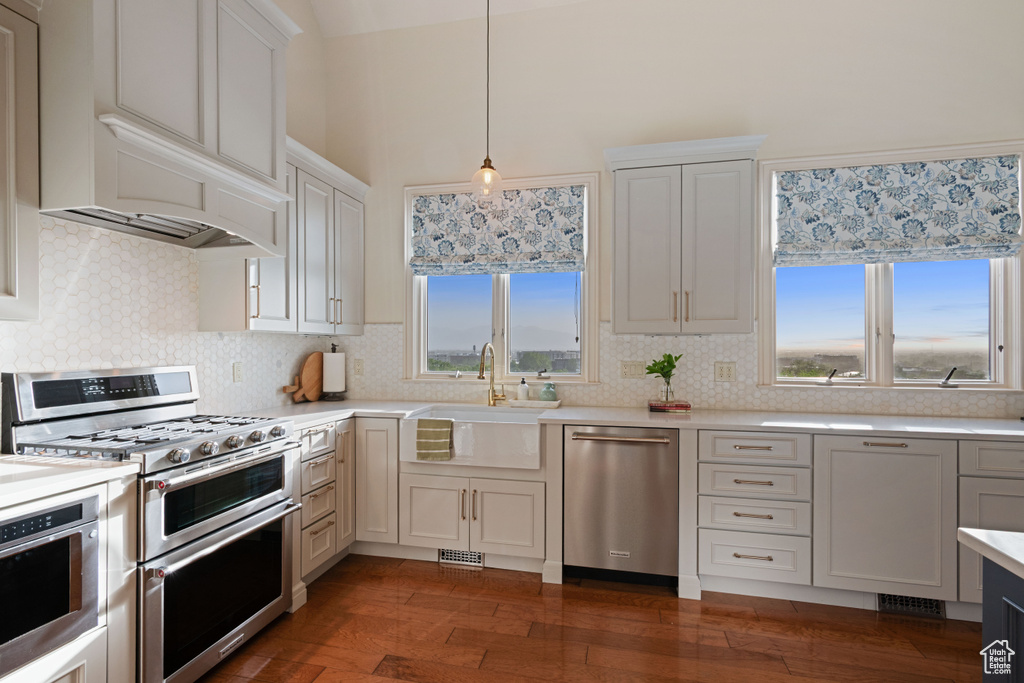 Kitchen with stainless steel appliances, a sink, light countertops, backsplash, and a high ceiling