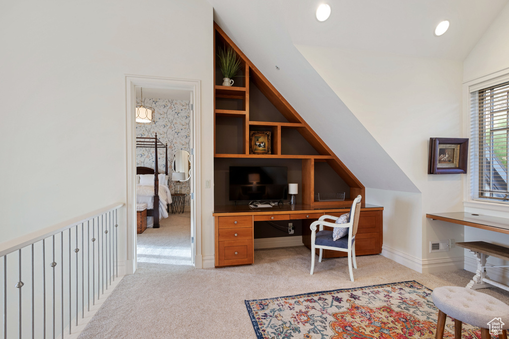 Office area with light carpet, lofted ceiling, and built in shelves