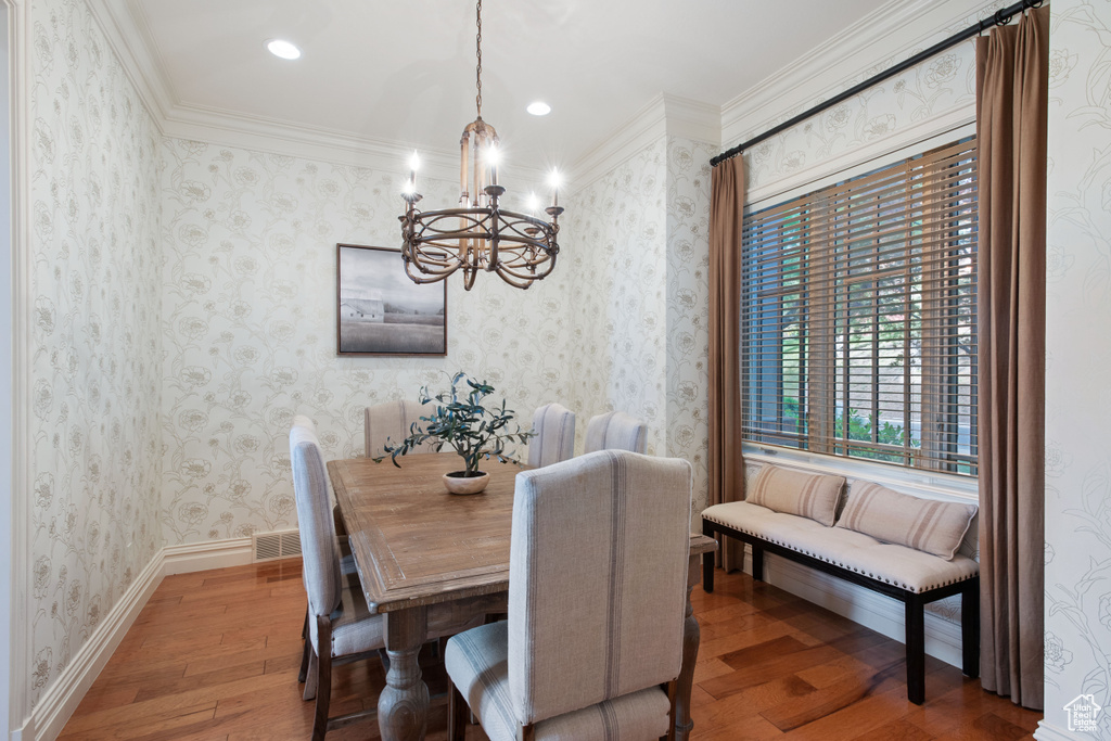 Dining space with a chandelier, hardwood / wood-style flooring, recessed lighting, and ornamental molding