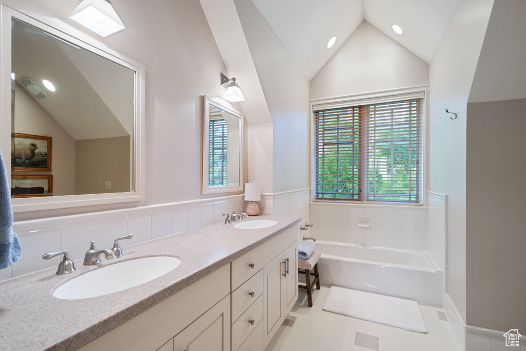 Bathroom featuring vaulted ceiling, a garden tub, double vanity, and recessed lighting