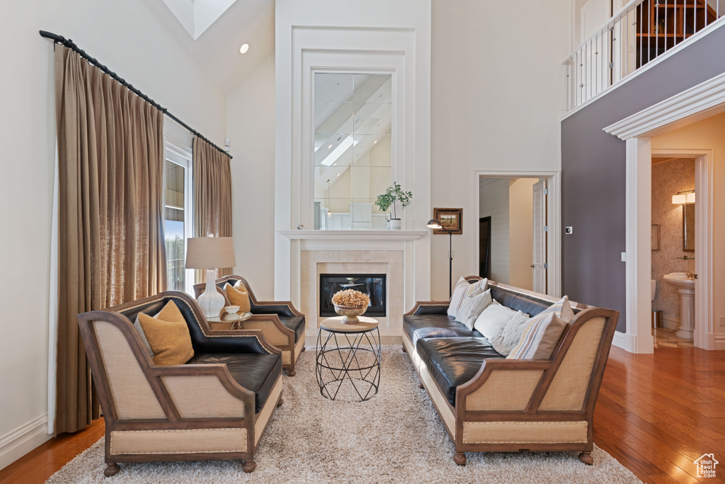 Living room with a towering ceiling, wood finished floors, a fireplace, baseboards, and a skylight