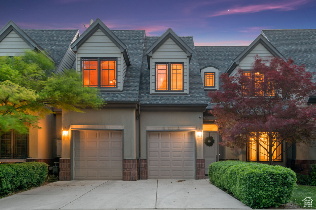 View of front facade with driveway, a garage, and a shingled roof
