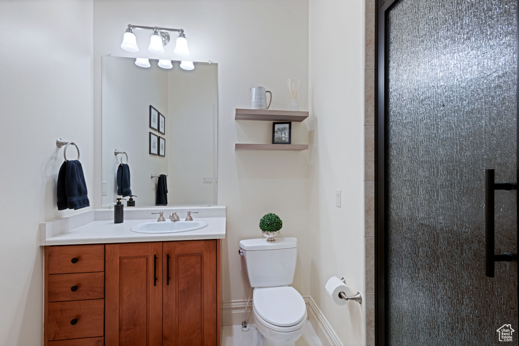 Bathroom with toilet, vanity, and a shower with door