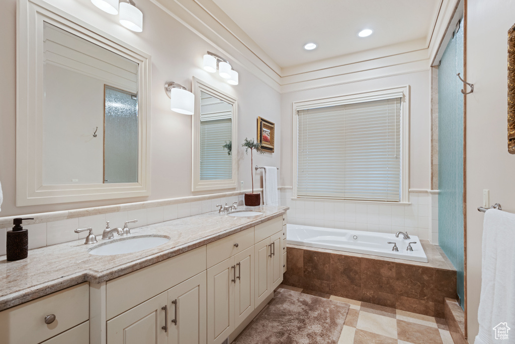 Full bathroom featuring double vanity, a garden tub, and recessed lighting