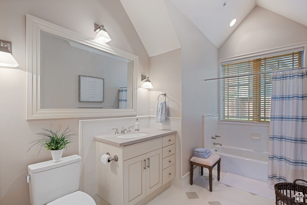 Full bath with vaulted ceiling, toilet, vanity, shower / tub combo with curtain, and tile patterned flooring