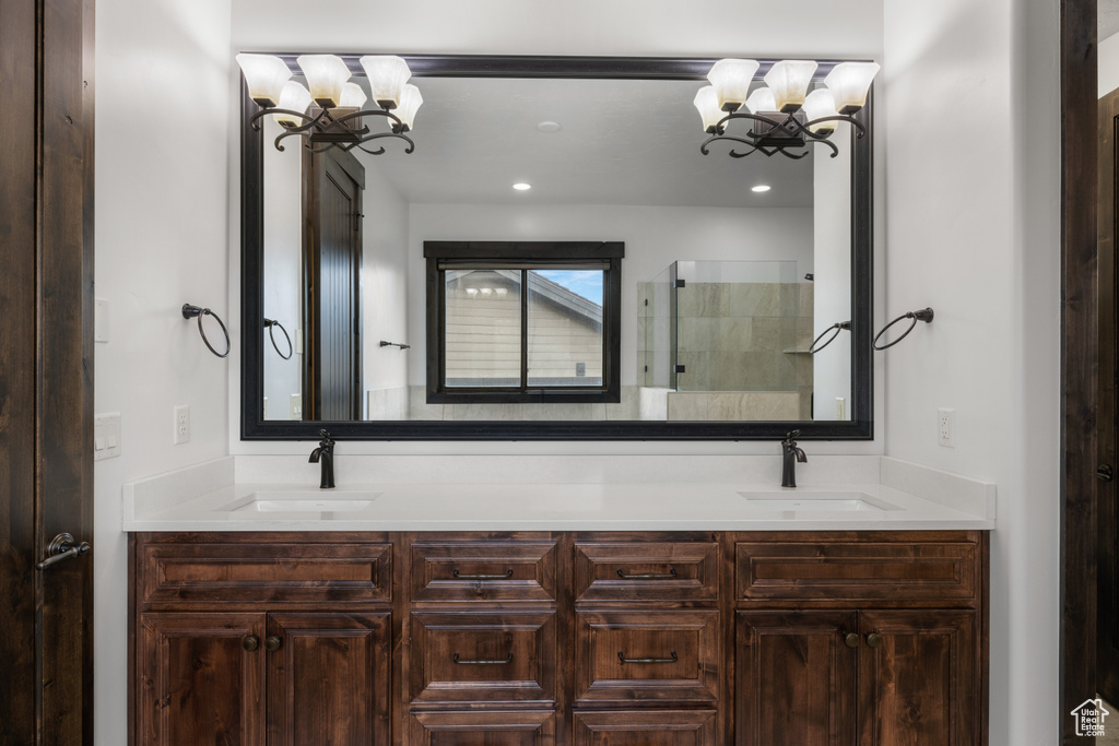 Bathroom featuring a chandelier, tiled shower, and double vanity