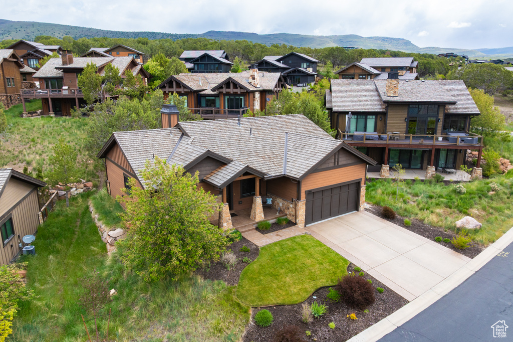 Rustic home featuring covered porch, concrete driveway, an attached garage, and a residential view
